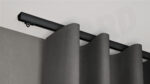Schwarze 1-läufige Aufputz-Gardinenschiene Modell 410 mit grauem Vorhang, verdeckt montiert an weißer Decke.