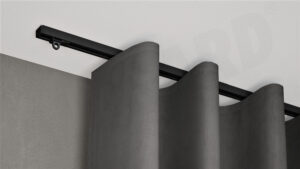 Schwarze 1-läufige Gardinenschiene Modell 850 mit verdeckter Montage, montiert an weißer Decke mit grauem Vorhang.