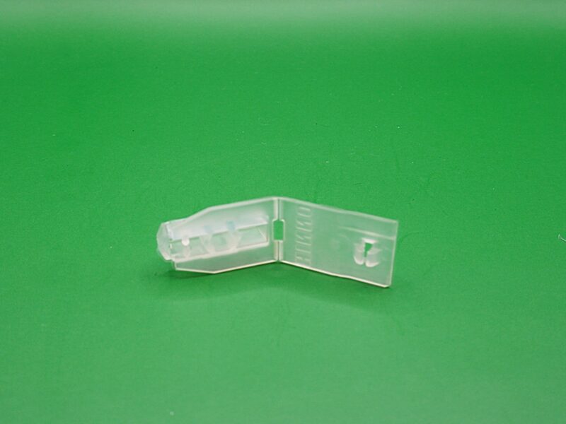 Transparenter Universalfeststeller fĂĽr Gardinenschienen mit 6 mm Laufbreite auf grĂĽnem Hintergrund.