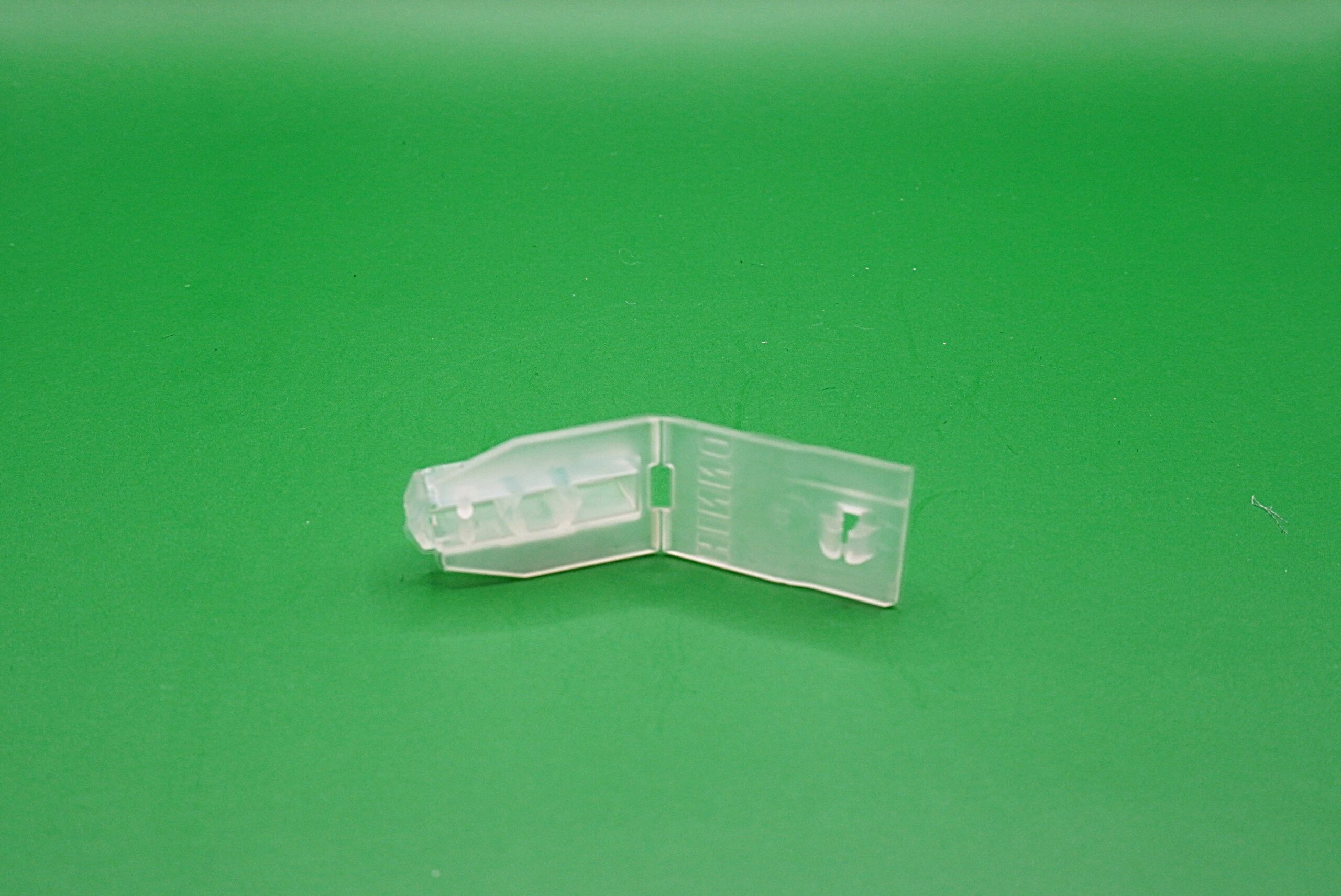 Universalfeststeller Gardinenschienen 6 mm Transparenter Universalfeststeller für Gardinenschienen mit 6 mm Laufbreite auf grünem Hintergrund.