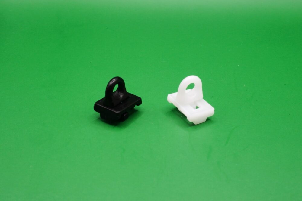 Zwischenfeststeller Gardinenschienen 6 mm Zwei Zwischenfeststeller für Gardinenschienen mit 6 mm Lauf in Schwarz und Weiß auf grünem Hintergrund.