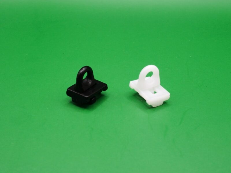 Zwei Zwischenfeststeller für Gardinenschienen mit 6 mm Lauf in Schwarz und Weiß auf grünem Hintergrund.