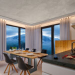Modernes Esszimmer mit LED-Gardinenschienen, bodenlangen Vorhängen und Panoramafenstern mit Bergblick.